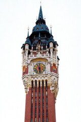 Ornate clock tower with red brick and dark spire against white sky