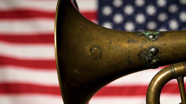 A Solemn Close-Up of an Aged Military Bugle Against a Waving American Flag, Symbolizing Honor and Sacrifice.