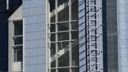 A paneled wall with a window and a staircase in sunlight. Urbanism, architecture, clean lines.
