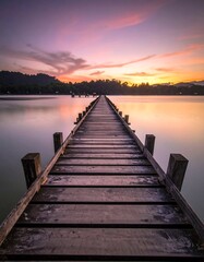 Obraz premium Wooden pier stretching to the horizon reflecting sunset colors