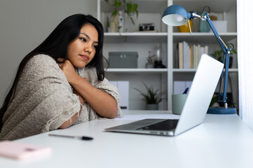 Latina woman feeling cold while working from home office