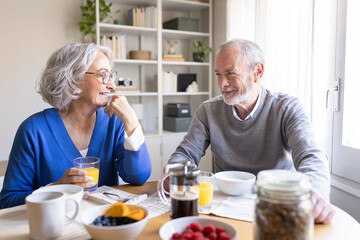 Happy senior couple enjoying breakfast and conversation at home