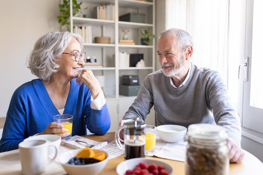 Happy senior couple enjoying breakfast and conversation at home
