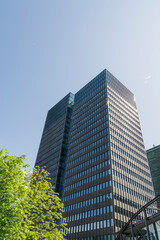 Modern office buildings stand tall against a clear blue sky in Oslo, Norway, with green trees adding a natural touch