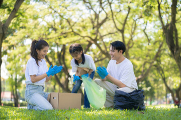 Happy Asian family collecting plastic bottles at the park.