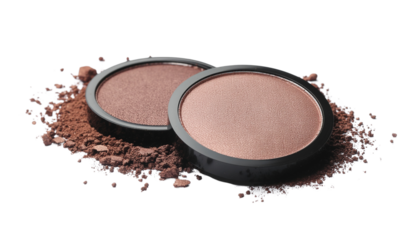 Two round eyeshadow palettes, light and dark brown, atop a scattering of brown powder isolated on solid white background in Png.
