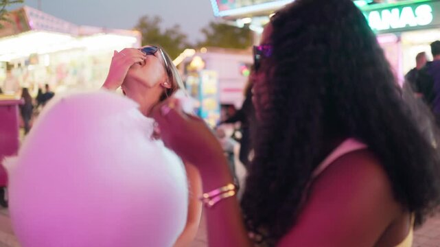 Multinational women friends sharing cotton candy at a fair
