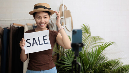 Young woman live streaming online sale at home clothing shop