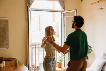 A man is dancing and holding the hand of a woman who is laughing next to him
