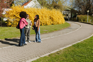 A group of three female friends standing while two of them talk