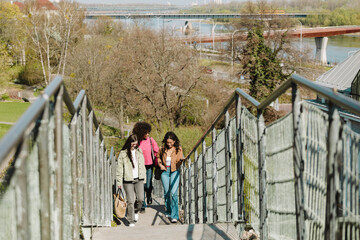 A group of three female friends are smiling and walking up the stairs