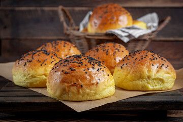 Homemade freshly baked plain golden brown soft hamburger buns topped with sesame seeds against wooden background. Homebaking, freshness, bbq concept