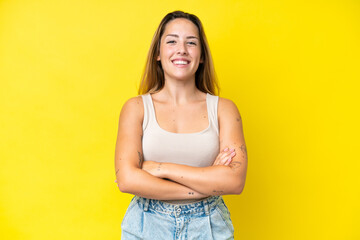 Young caucasian woman isolated on yellow background keeping the arms crossed in frontal position