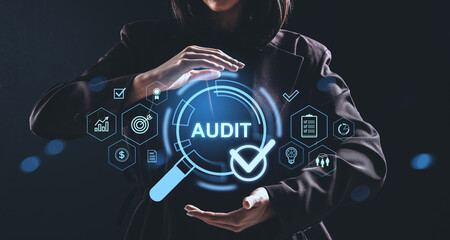 Businesswoman interacting with glowing audit concept hologram and financial icons on dark background.