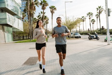 Obraz premium A male athlete is talking to a female athlete running next to him and smiling