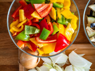 Fresh chopped vegetables: white onion, colorful bell peppers, eggplant on wooden table. Top view