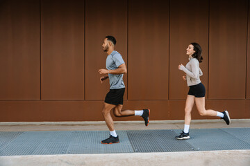 The female athlete laughs and runs behind the male athlete in front of her