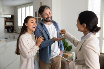 Overjoyed husband wife get keys from apartment from female realtor