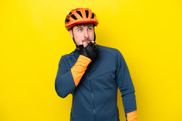 Young cyclist caucasian man isolated on yellow background having doubts and thinking