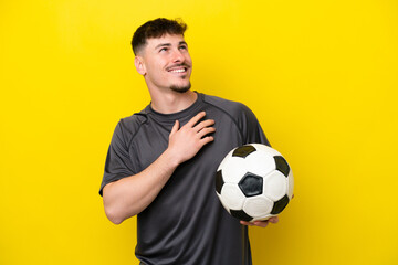 Young football player man isolated on yellow background looking up while smiling