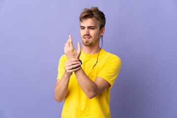 Young handsome blonde man isolated on purple background suffering from pain in hands