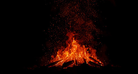 Glowing campfire with flying sparks in the dark night