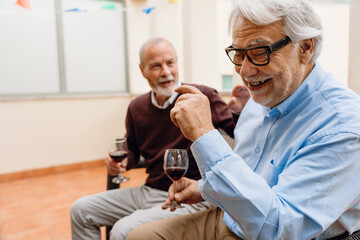 Obraz premium A man laughs and listens to his male friend sitting next to him while they hold glasses