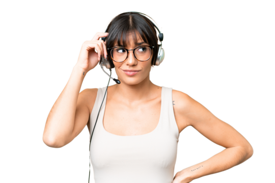 Telemarketer caucasian woman working with a headset over isolated background having doubts and with confuse face expression