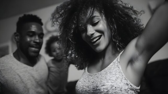 A Black family enjoys a spontaneous dance together in their home captured in a black and white joyful moment