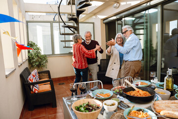 A group of four friends dance in pairs at a table and hold hands while one of them laughs