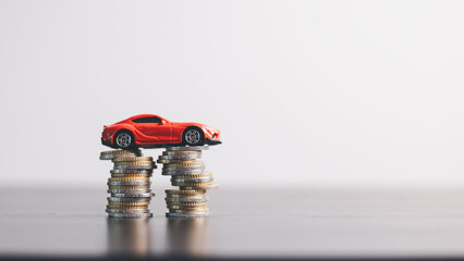 Red car model on stacked coins, symbolizing auto loan, car finance, investment, insurance and...