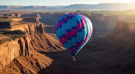 A colorful hot air balloon soaring above a rocky canyon landscape