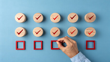 Hand completing a checklist with wooden circles and red check marks, placing a red square to signify completion on a blue textured background