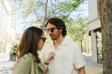Obraz premium A woman buttons up a shirt on a man who hugs her while standing next to her