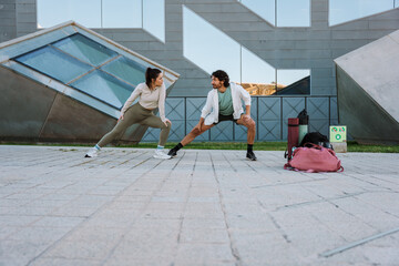 A man and a woman stretch their legs and look at each other