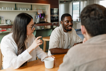 Obraz premium A group of three workers are sitting at a table while one of them is talking