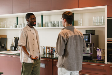 Fototapeta premium A male employee is talking to a male employee standing next to him at a coffee machine