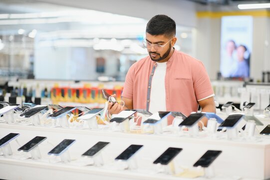 Indian man customer buyer at mobile phone store choose his new smartphone