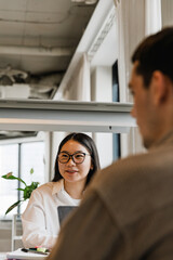 Obraz premium A female employee is smiling and sitting at a desk across from a male employee