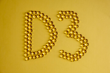 Capsules of vitamin D3 on a yellow background with free space. Biologically active substances of the calciferol group are fat-soluble organic compounds.