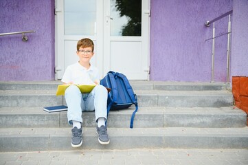 Portrait of a junior high school student sitting and reading a book near the school. Learning...