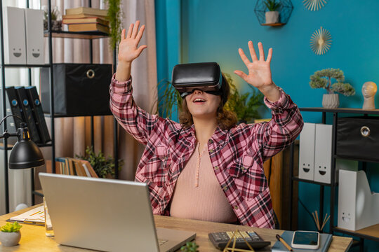 Happy business woman using virtual reality futuristic technology VR app headset to simulation 3D 360 video at modern home office workplace. Excited manager freelancer. Remote distant online working.