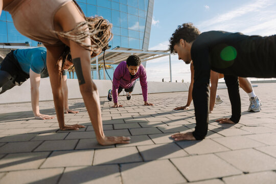 A group of five athletes are resting their hands on the ground in a push-up position