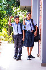 Indian Cheerful school kids in uniform smile at camera while standing outdoors on a sunny school day