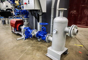 Industrial pump system with bright blue valves and grey pipes on a concrete floor, showcasing...