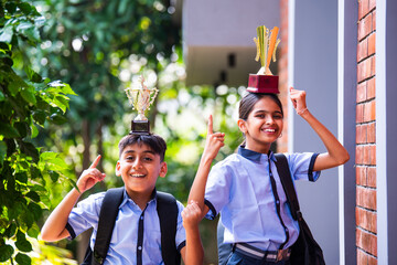 Indian School Kids in Uniform Flaunting Trophy Proudly While Standing Outside and Looking at Camera