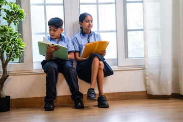 Indian Uniformed students quietly read near classroom window during peaceful self-study time