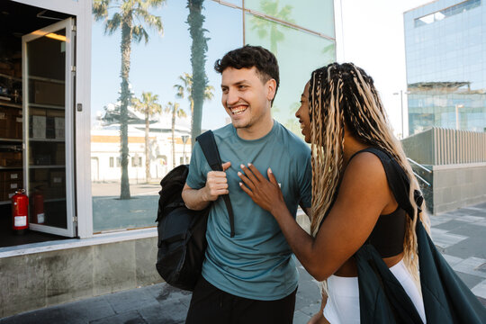 A female athlete puts her hand on the chest of a male athlete walking next to her while they laugh