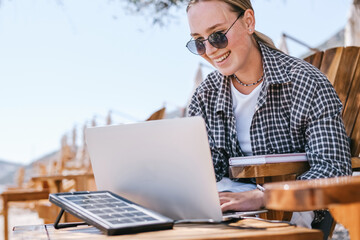Beach workation digital nomad plans tasks with laptop and notebook on lounge chairs, powered by a...
