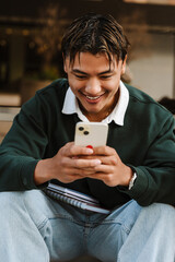 A male student types on the phone and laughs while sitting